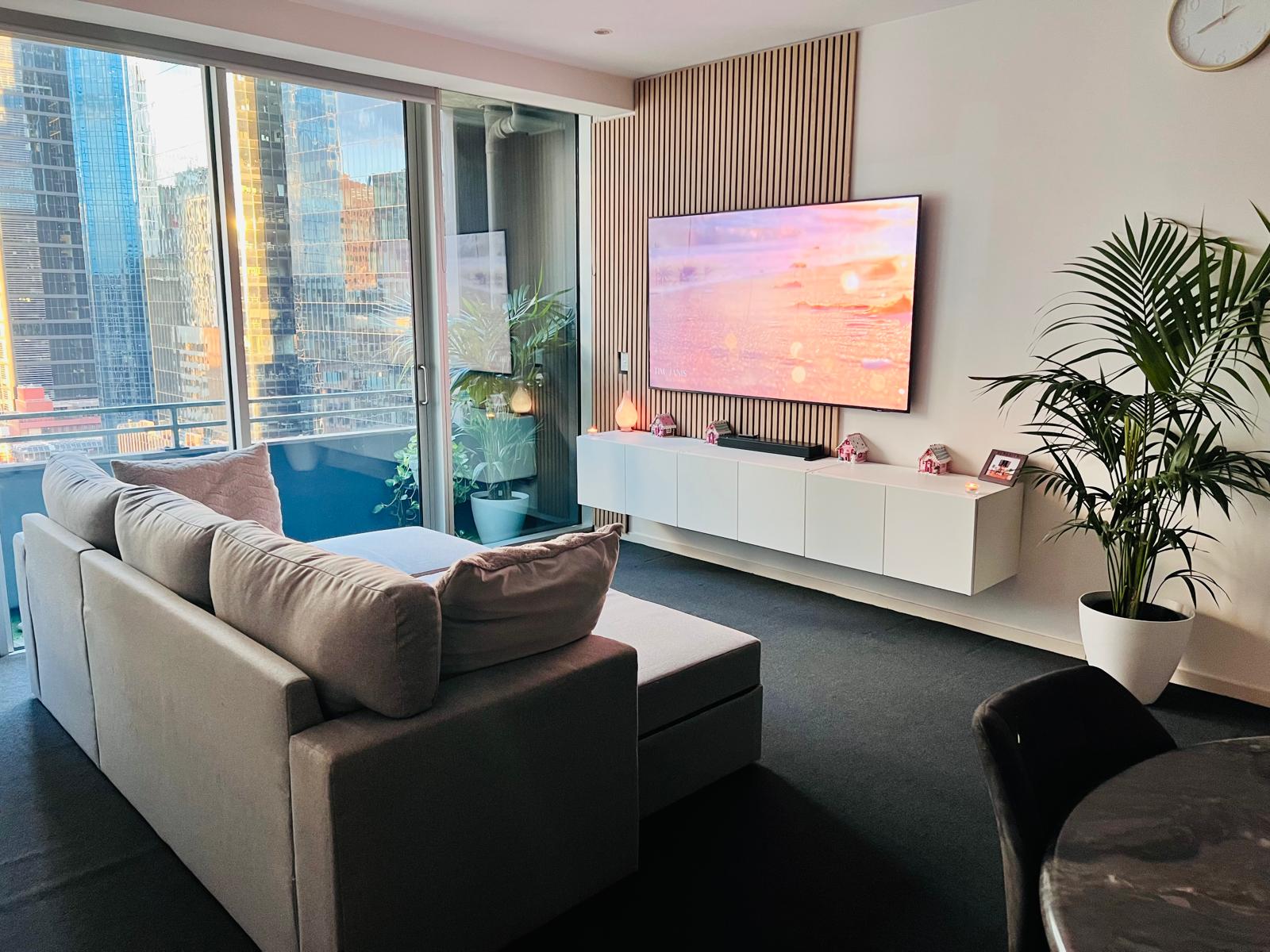 Aurora Residence — living room with Melbourne CBD skyline at golden hour